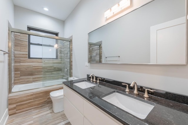 full bathroom featuring vanity, combined bath / shower with glass door, and toilet