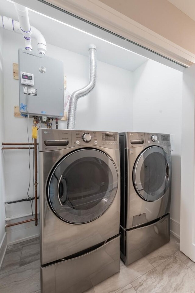 laundry area featuring washing machine and dryer, water heater, and light tile patterned floors