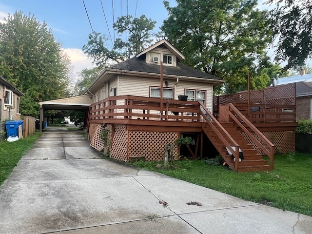 back of property with a carport, a lawn, and a wooden deck