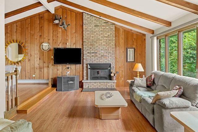 living room featuring brick wall, vaulted ceiling with beams, a fireplace, and hardwood / wood-style floors