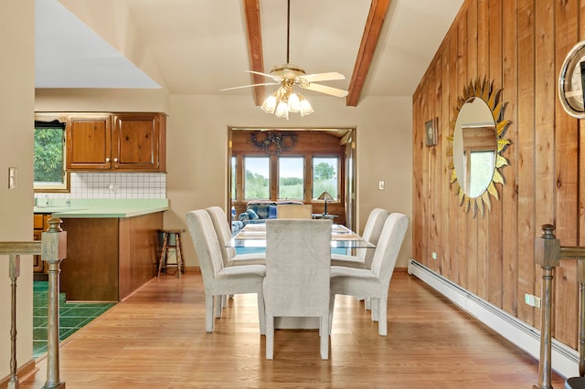 dining area featuring vaulted ceiling with beams, light hardwood / wood-style flooring, wooden walls, a baseboard heating unit, and ceiling fan