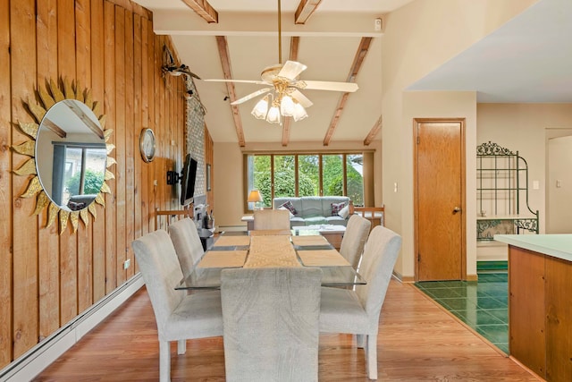 dining room featuring vaulted ceiling with beams, wooden walls, a baseboard heating unit, ceiling fan, and wood-type flooring