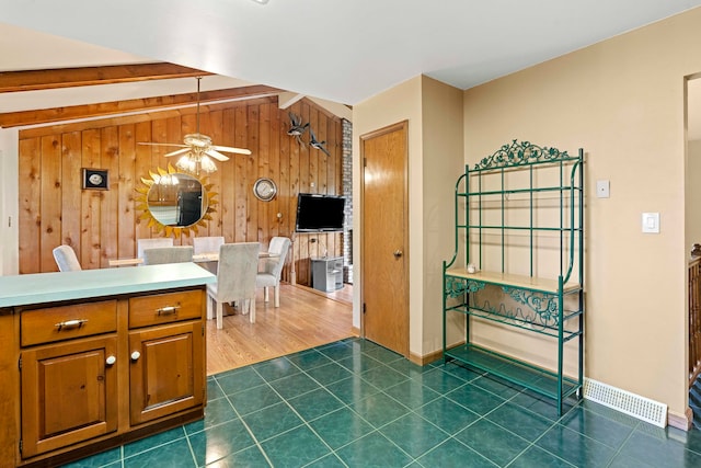 kitchen with wooden walls, dark tile patterned flooring, and ceiling fan