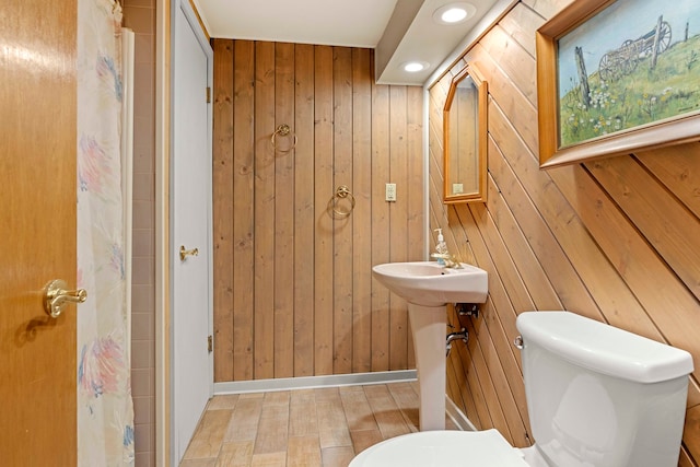 bathroom featuring wood walls and toilet