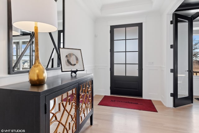 entryway with light wood-type flooring and a raised ceiling