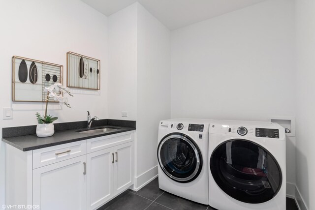 clothes washing area with sink, cabinets, washer and dryer, and dark tile patterned flooring