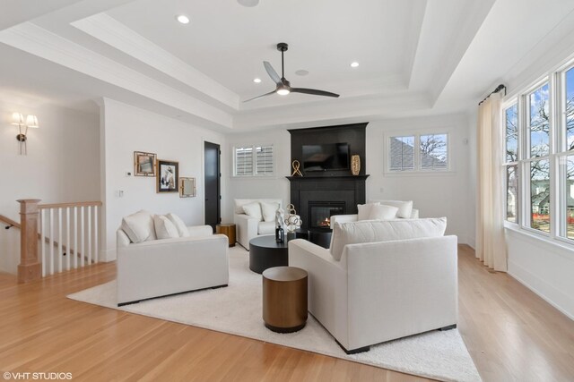 living room with a tray ceiling, light hardwood / wood-style flooring, and a wealth of natural light