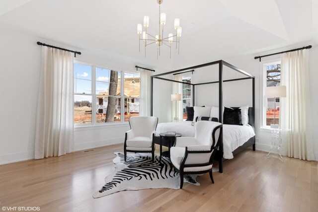 bedroom with lofted ceiling, light hardwood / wood-style floors, multiple windows, and an inviting chandelier