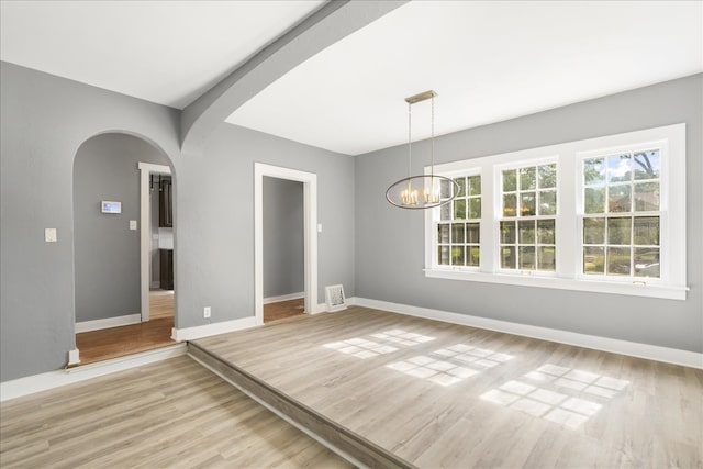 unfurnished dining area with light hardwood / wood-style flooring and a chandelier