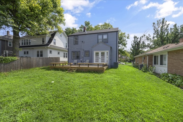 rear view of property featuring french doors, cooling unit, a lawn, and a wooden deck