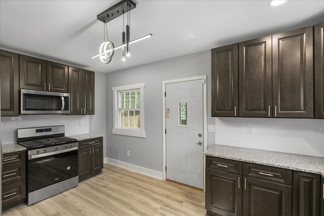 kitchen with tasteful backsplash, stainless steel appliances, hanging light fixtures, light wood-type flooring, and dark brown cabinetry