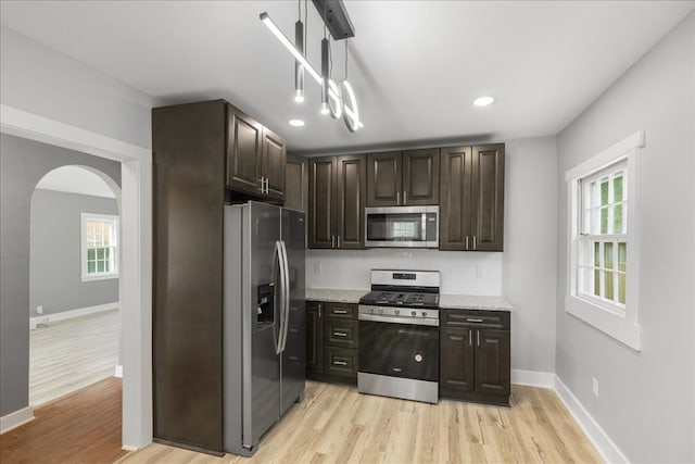 kitchen with light stone counters, light hardwood / wood-style floors, dark brown cabinetry, and appliances with stainless steel finishes