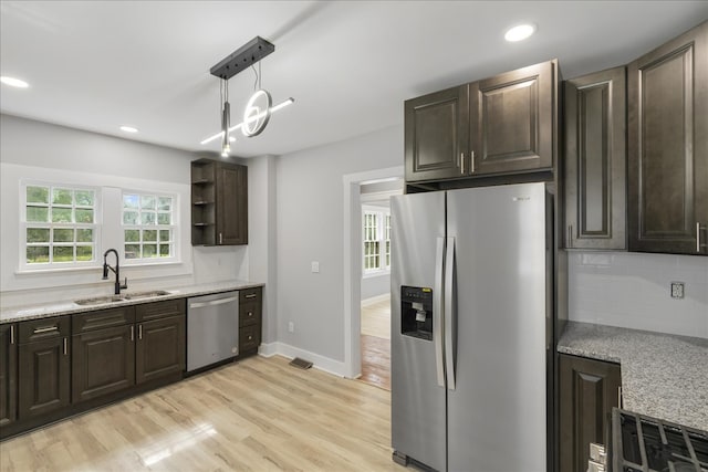 kitchen featuring light hardwood / wood-style floors, light stone countertops, appliances with stainless steel finishes, pendant lighting, and sink