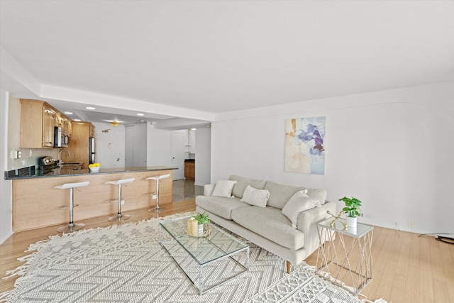 living room featuring sink and light hardwood / wood-style flooring