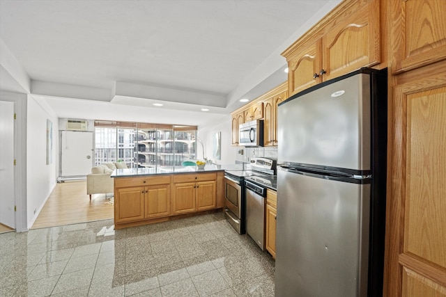 kitchen featuring a wall unit AC, appliances with stainless steel finishes, baseboard heating, light hardwood / wood-style floors, and kitchen peninsula