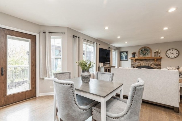 dining space with a stone fireplace and light wood-type flooring