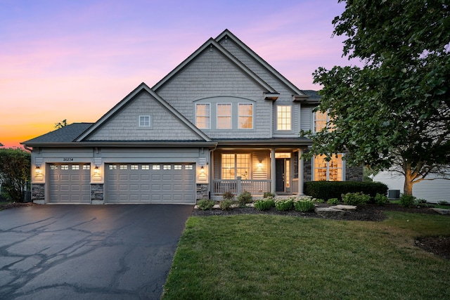 view of front facade featuring a garage, covered porch, and a yard