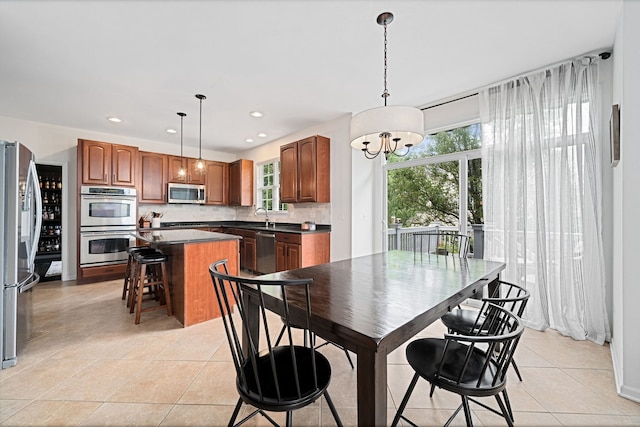 tiled dining space with a healthy amount of sunlight, sink, and an inviting chandelier