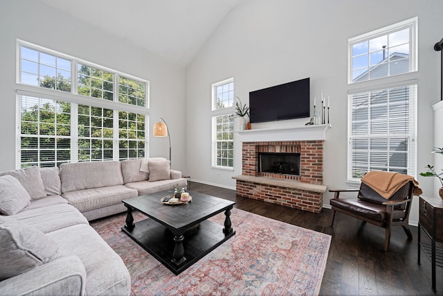 living room with a healthy amount of sunlight, dark wood-type flooring, high vaulted ceiling, and a brick fireplace