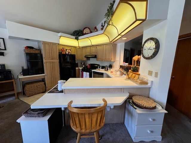 kitchen with sink, stainless steel range, kitchen peninsula, black fridge, and a kitchen bar