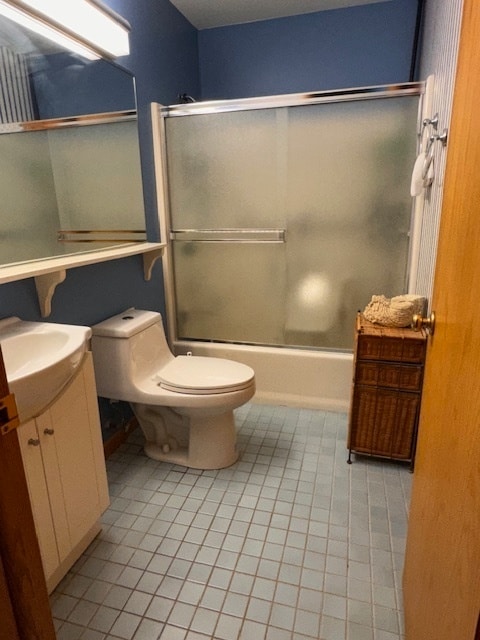 full bathroom featuring vanity, toilet, bath / shower combo with glass door, and tile patterned floors