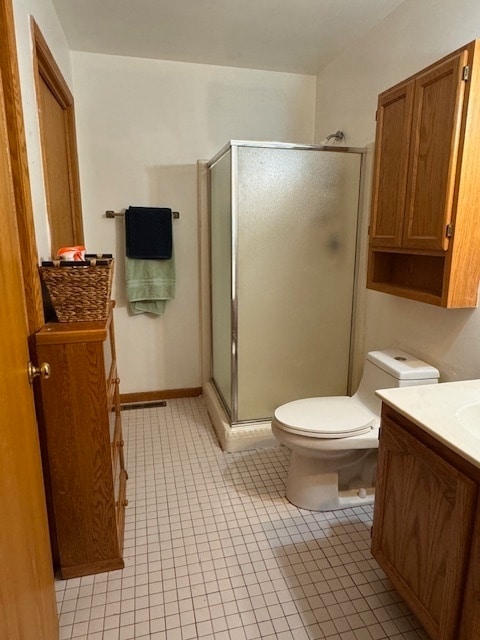 bathroom featuring vanity, toilet, tile patterned floors, and a shower with shower door