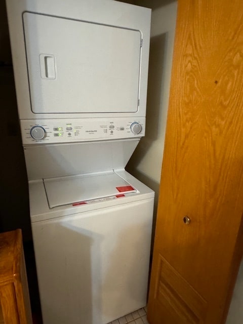 washroom with light tile patterned floors and stacked washer / drying machine