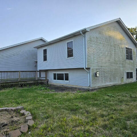 rear view of house featuring a wooden deck and a lawn