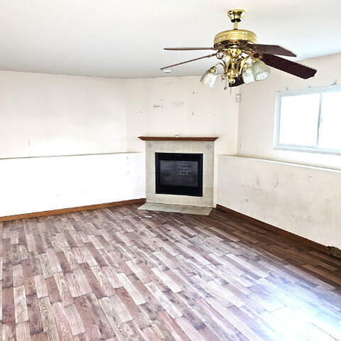 unfurnished living room with hardwood / wood-style flooring, a tile fireplace, and ceiling fan