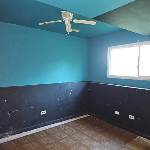 spare room with ceiling fan and dark parquet floors