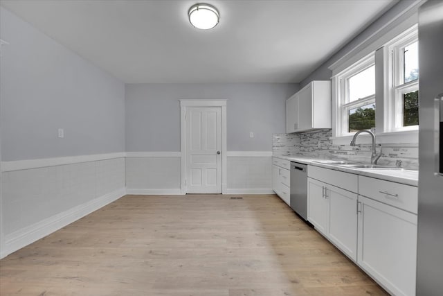 kitchen featuring light hardwood / wood-style flooring, sink, stainless steel dishwasher, decorative backsplash, and white cabinetry