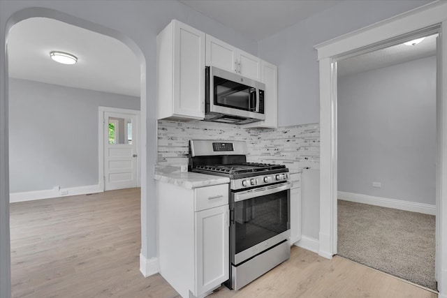 kitchen featuring decorative backsplash, light wood-type flooring, stainless steel appliances, and white cabinets