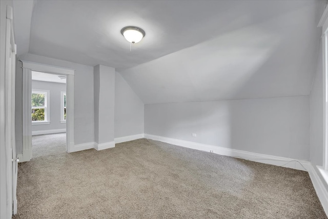 bonus room with light carpet and vaulted ceiling