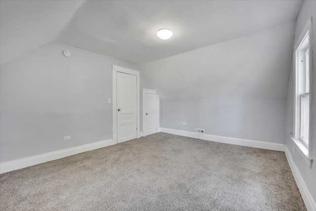 bonus room with lofted ceiling and light colored carpet