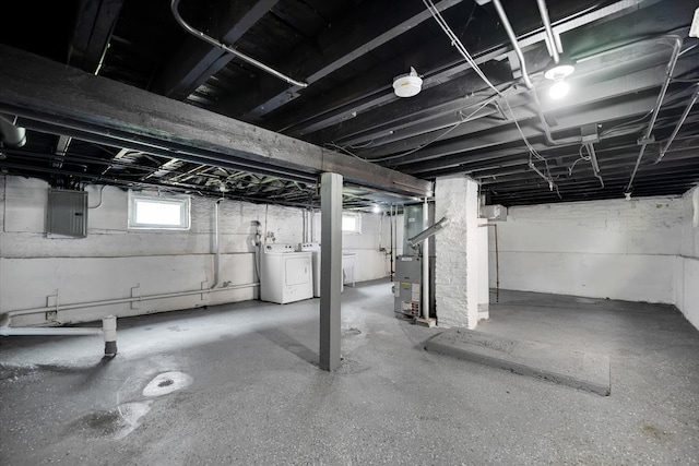 basement featuring heating unit, washer and clothes dryer, and electric panel