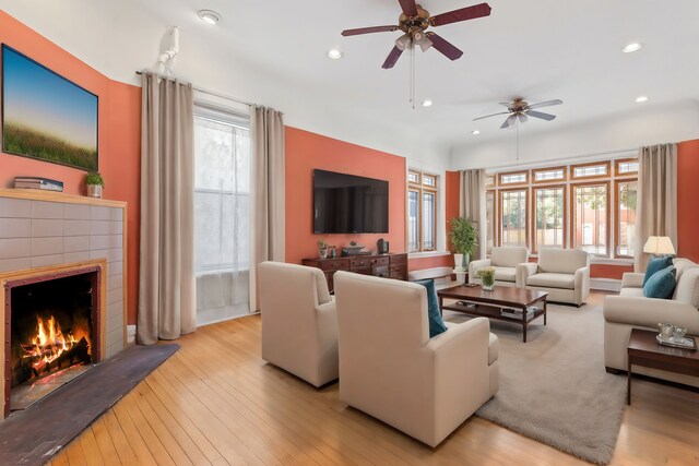 living room with a tiled fireplace, plenty of natural light, and light hardwood / wood-style floors