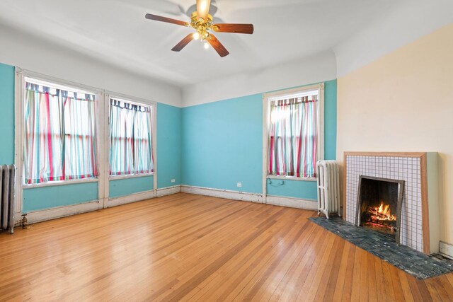 unfurnished living room with a wealth of natural light, radiator, and light hardwood / wood-style floors