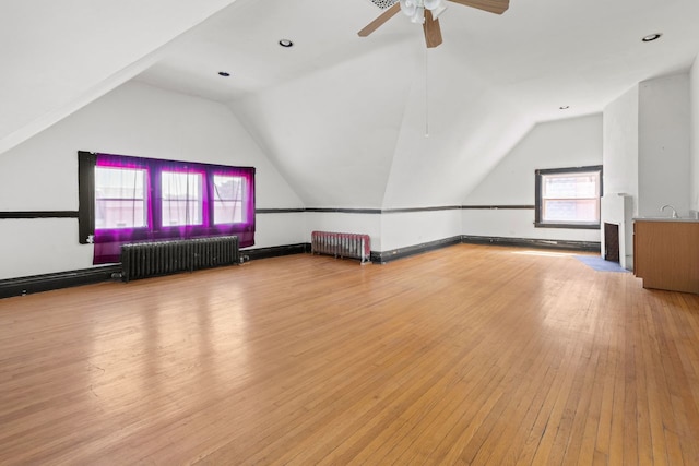 additional living space featuring ceiling fan, radiator, light hardwood / wood-style flooring, and vaulted ceiling