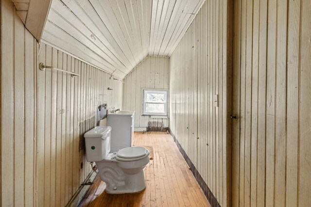 bathroom with lofted ceiling, hardwood / wood-style floors, wooden walls, and toilet