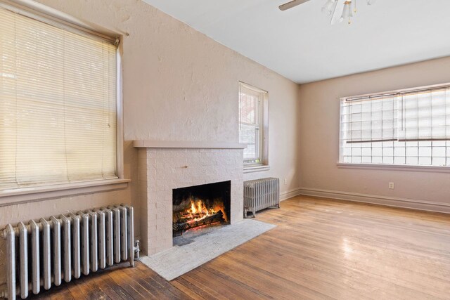 unfurnished living room with ceiling fan, radiator heating unit, and wood-type flooring