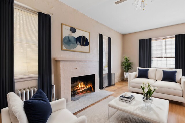 living room featuring radiator heating unit, light hardwood / wood-style flooring, and ceiling fan