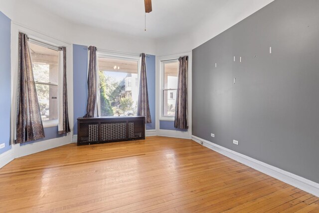 spare room with radiator, ceiling fan, and light hardwood / wood-style floors