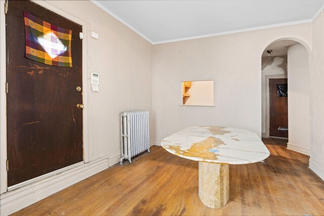 entrance foyer featuring hardwood / wood-style floors, ornamental molding, and radiator heating unit