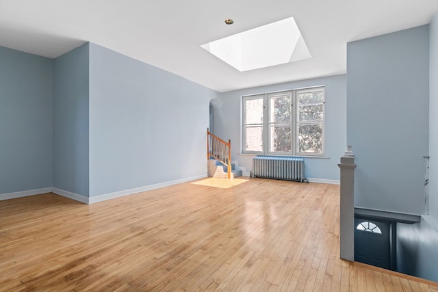 bonus room featuring a skylight, radiator heating unit, and light hardwood / wood-style floors