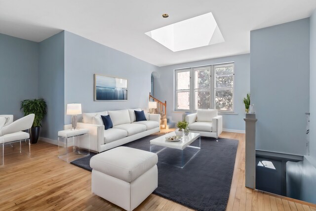 living room featuring light hardwood / wood-style flooring and a skylight