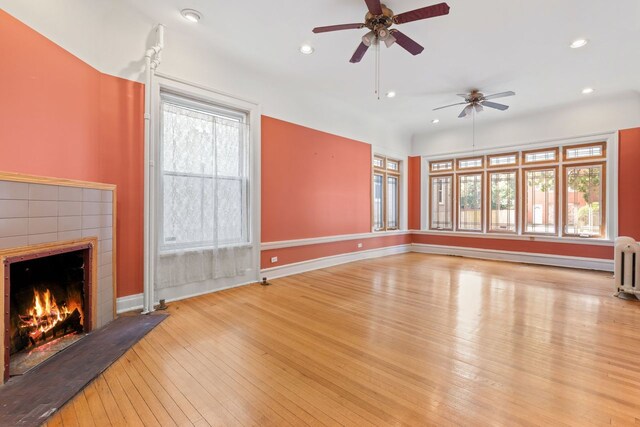 unfurnished living room featuring ceiling fan, a fireplace, a healthy amount of sunlight, and light hardwood / wood-style floors