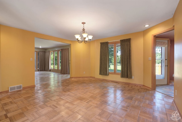 unfurnished room featuring a wealth of natural light, light parquet floors, and an inviting chandelier