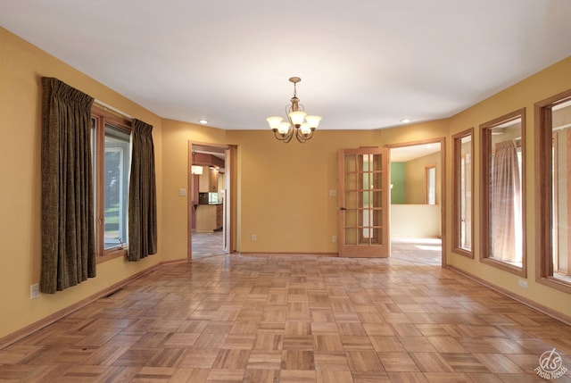 empty room with light parquet flooring and a chandelier