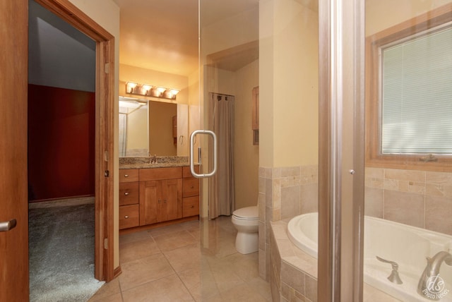 bathroom with tile patterned floors, tiled tub, vanity, and toilet