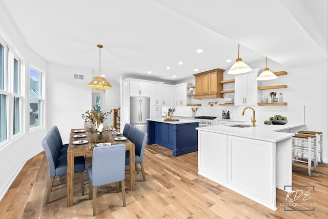 kitchen featuring open shelves, stainless steel fridge, a sink, light countertops, and blue cabinets